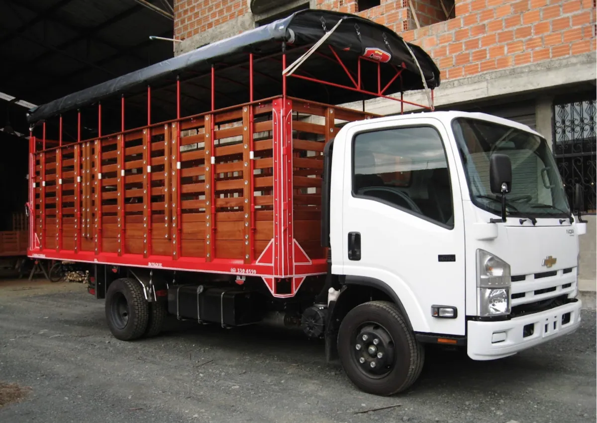 Camión blanco con carrocería de estacas en madera y estructura roja
