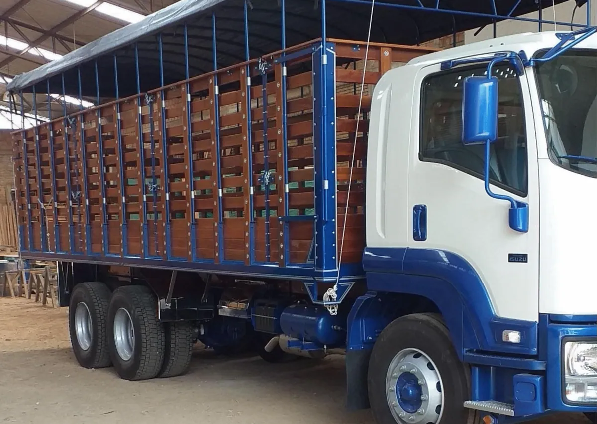 Camión azul de doble eje con carrocería de estacas en madera