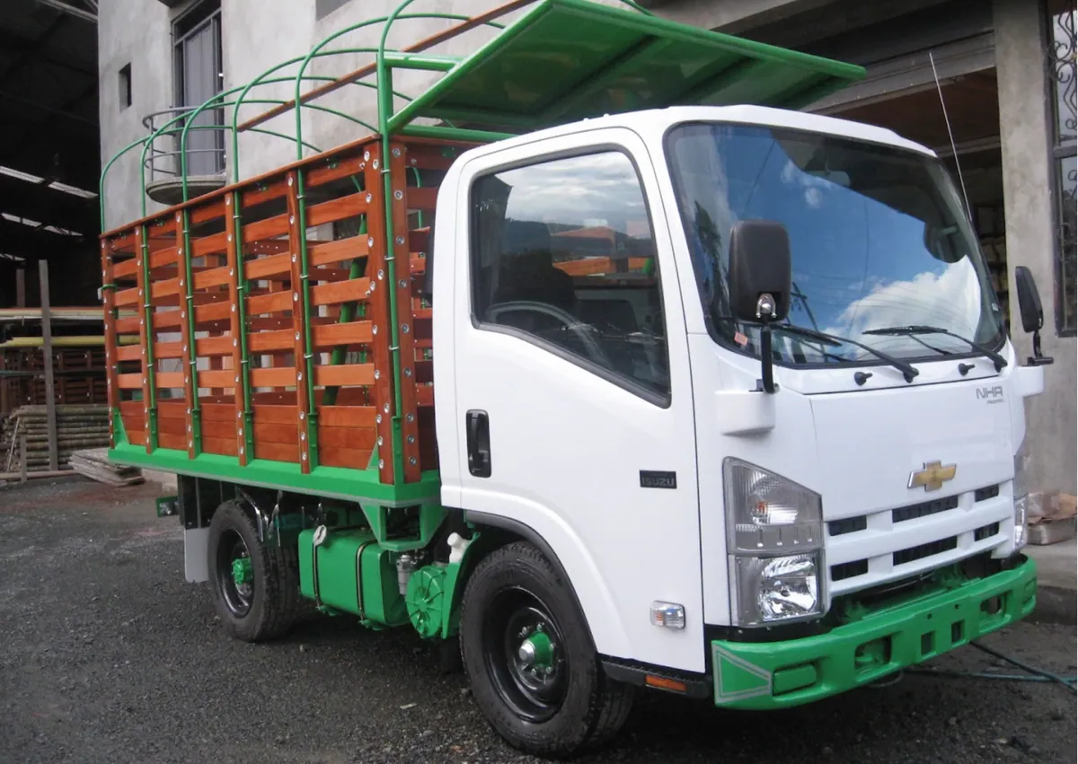 Camión blanco con carrocería de estacas en madera y estructura verde
