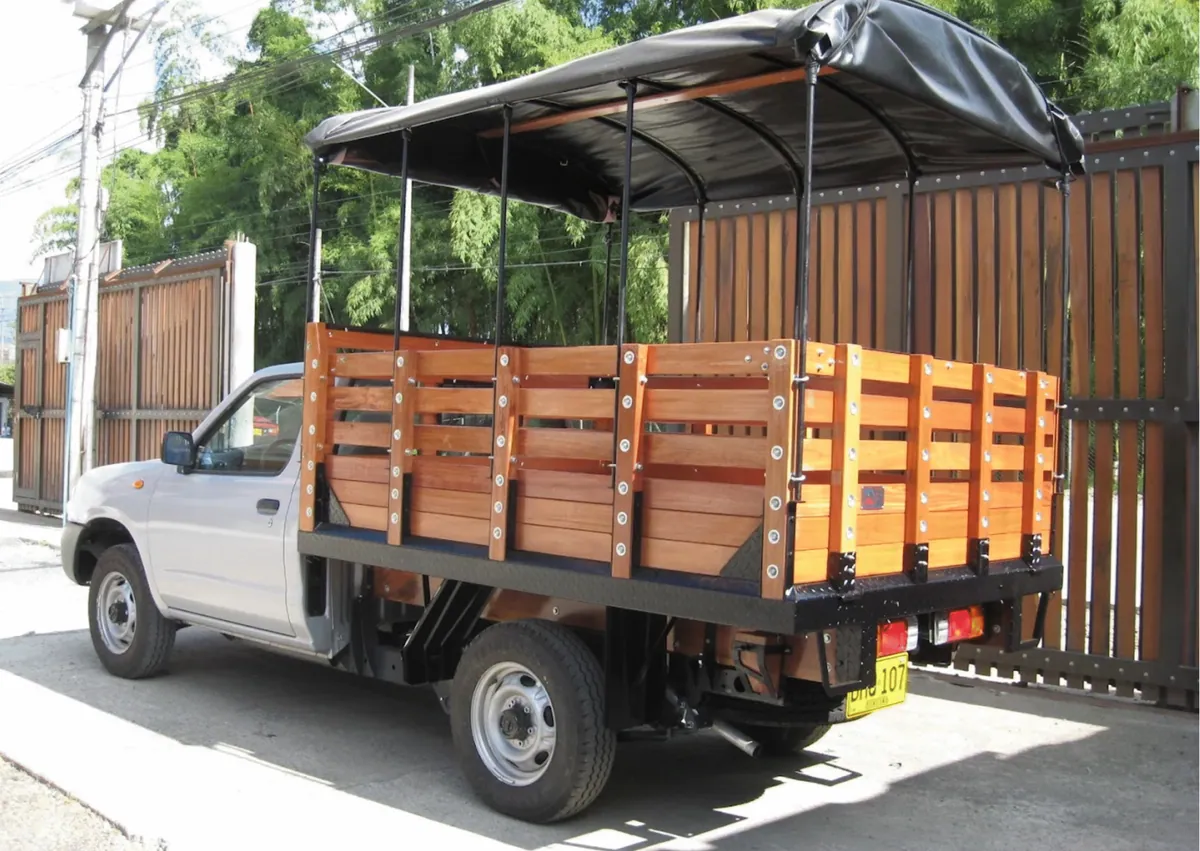 Camioneta con carrocería de estacas en madera y carpa negra