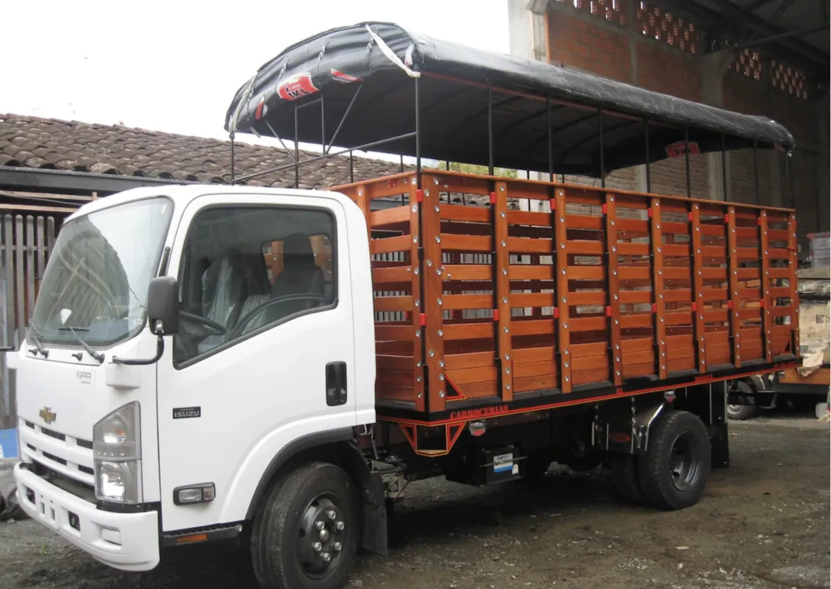 Camión blanco con carrocería de estacas en madera y carpa negra